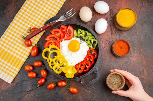 Vue de dessus savoureuse omelette avec des poivrons tranchés et des assaisonnements sur la table sombre