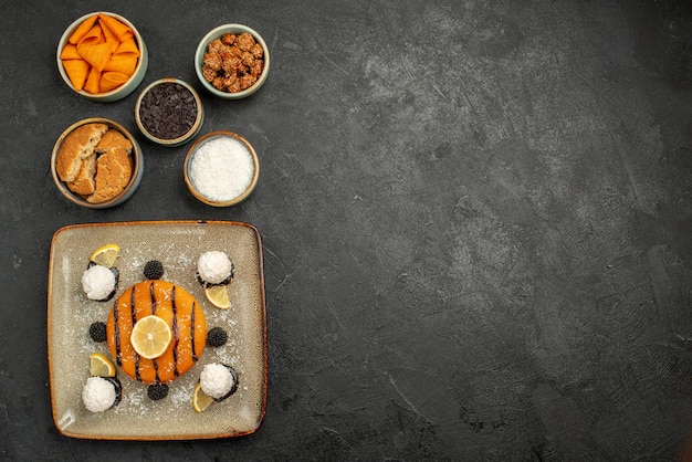 Vue de dessus savoureuse petite tarte avec des bonbons à la noix de coco sur une surface sombre tarte biscuit dessert gâteau biscuit thé bonbons