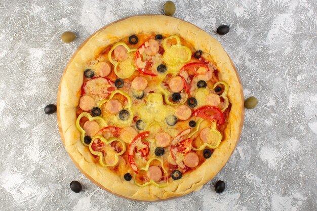 Vue de dessus savoureuse pizza au fromage avec saucisses aux olives et tomates rouges sur le bureau gris repas de pâte italienne de restauration rapide