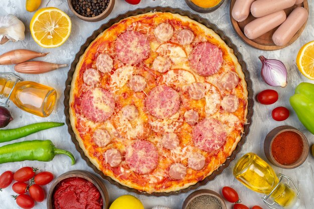 Vue de dessus savoureuse pizza à la saucisse avec des légumes frais sur une table blanche couleur du four gâteau à tarte cuire une pizza italie fast-food