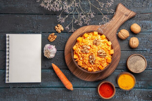 Vue de dessus savoureuse salade de carottes aux noix et assaisonnements sur un bureau bleu foncé salade de noix régime alimentaire couleur nourriture