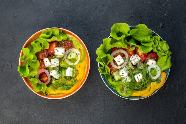 Vue de dessus savoureuse salade de légumes avec concombres au fromage et tomates sur fond sombre