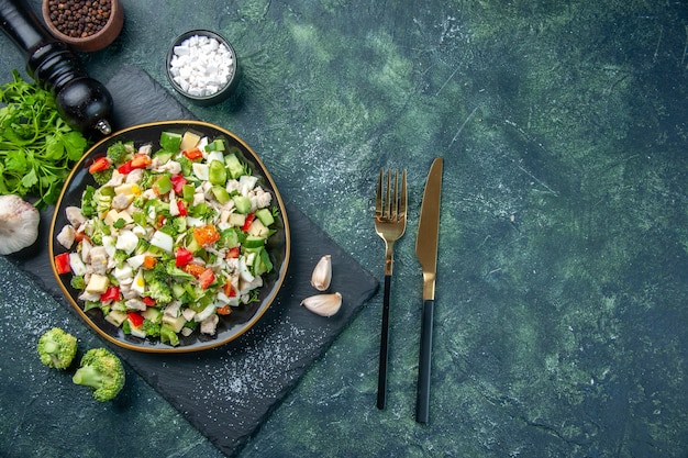 Vue de dessus savoureuse salade de légumes à l'intérieur de la plaque sur fond bleu foncé couleur cuisine déjeuner restaurant repas régime alimentaire