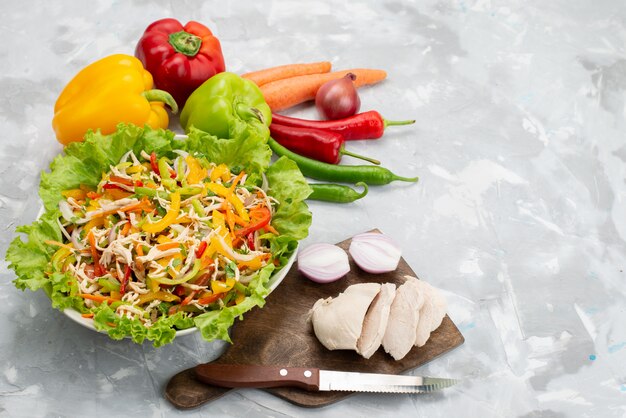 Vue de dessus savoureuse salade de légumes avec des légumes en tranches et des légumes frais entiers et poitrine de poulet crue sur gris, repas de salade