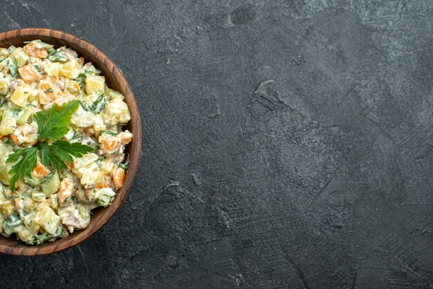 Vue de dessus savoureuse salade mayyonaise à l'intérieur de la plaque brune sur fond noir