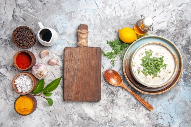 Vue de dessus savoureuse soupe au yogourt dovga avec des verts sur un bureau blanc plat de soupe au lait laitier