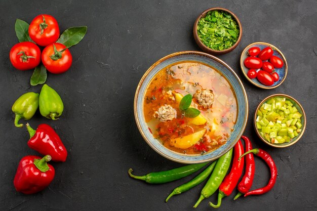 Vue de dessus savoureuse soupe aux boulettes de viande avec des légumes verts et du poivre sur la couleur du plat de sauce au sol sombre