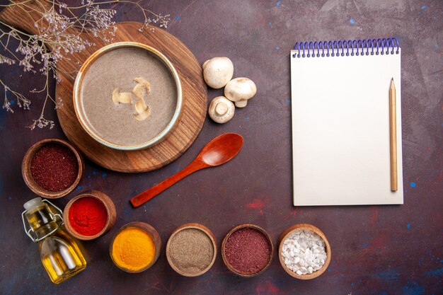 Vue de dessus savoureuse soupe aux champignons avec différents assaisonnements sur le fond sombre soupe aux champignons assaisonnement repas alimentaire