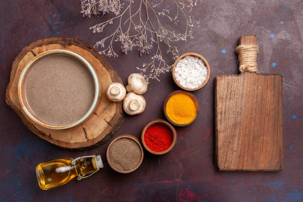 Vue de dessus savoureuse soupe aux champignons avec différents assaisonnements sur fond violet foncé assaisonnement soupe repas alimentaire