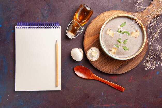 Vue de dessus savoureuse soupe aux champignons à l'intérieur de la plaque sur fond sombre soupe légumes repas dîner nourriture