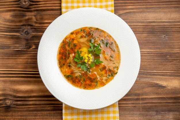 Vue de dessus savoureuse soupe aux légumes avec des verts sur table en bois brun soupe alimentaire assaisonnement