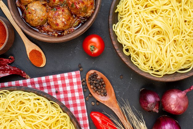 Vue de dessus savoureuse soupe de boulettes de viande dans un bol de spaghettis dans un bol d'oignons rouges cuillères en bois sur table