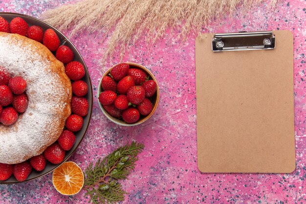 Vue de dessus savoureuse tarte aux fraises avec du sucre en poudre sur rose clair