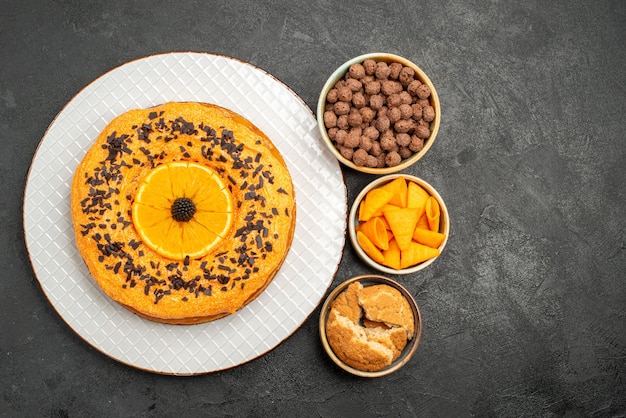 Vue de dessus savoureuse tarte sucrée avec des tranches d'orange sur une surface sombre tarte gâteau dessert thé biscuit sucré