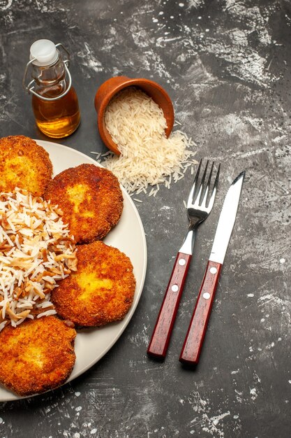 Vue de dessus de savoureuses côtelettes frites avec du riz cuit sur la viande de photo de repas de surface sombre