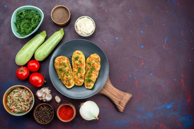 Vue de dessus de savoureuses courges cuites au four avec des légumes verts avec des assaisonnements de légumes frais sur une surface sombre