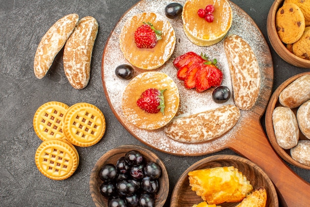 Photo gratuite vue de dessus de savoureuses crêpes avec différents bonbons sur le dessert de gâteau au sucre surface sombre