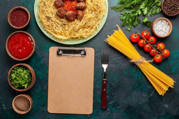 Photo gratuite vue de dessus de savoureuses pâtes italiennes avec des boulettes de viande et différents assaisonnements sur le bureau bleu foncé