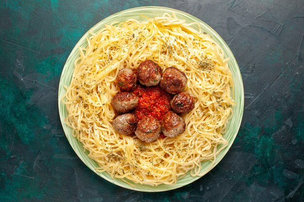 Vue de dessus de savoureuses pâtes italiennes avec des boulettes de viande sur le fond bleu foncé