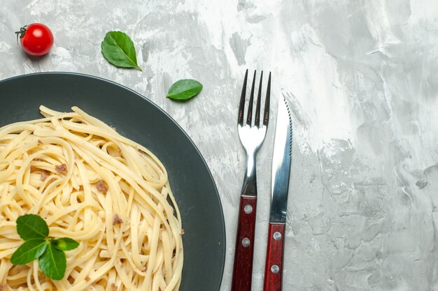 Vue de dessus de savoureuses pâtes italiennes avec des couverts sur un bureau clair couleur repas plat nourriture photo pâte