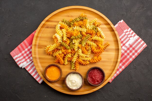 Vue de dessus de savoureuses pâtes italiennes pâtes en spirale cuites inhabituelles avec assaisonnements sur dark