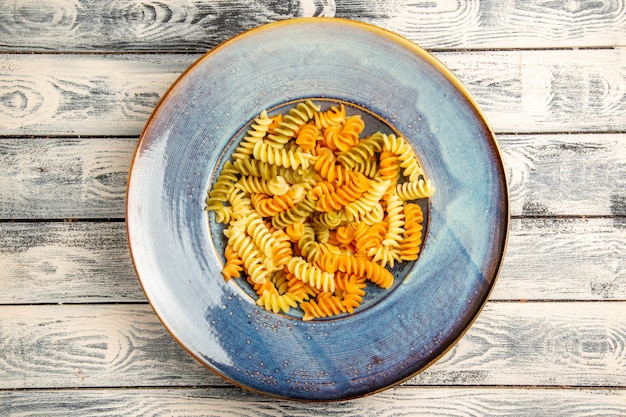 Vue de dessus de savoureuses pâtes italiennes pâtes en spirale cuites inhabituelles sur bois gris