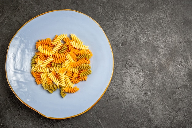 Vue de dessus de savoureuses pâtes italiennes pâtes en spirale cuites inhabituelles sur le noir