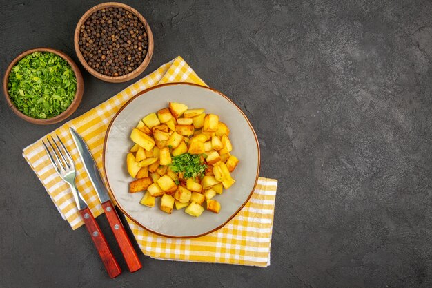 Vue de dessus de savoureuses pommes de terre frites à l'intérieur de la plaque sur la surface gris foncé