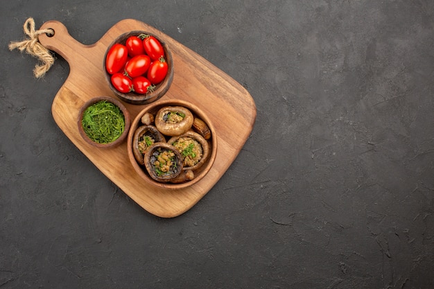 Vue de dessus savoureux champignons cuits avec des tomates sur fond sombre