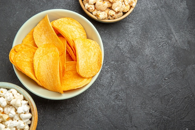 Vue de dessus de savoureux chips de fromage avec différentes collations sur le fond sombre