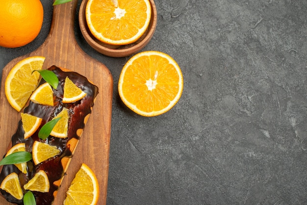 Photo gratuite vue de dessus de savoureux gâteaux entiers et coupés d'oranges sur une planche à découper sur tableau noir