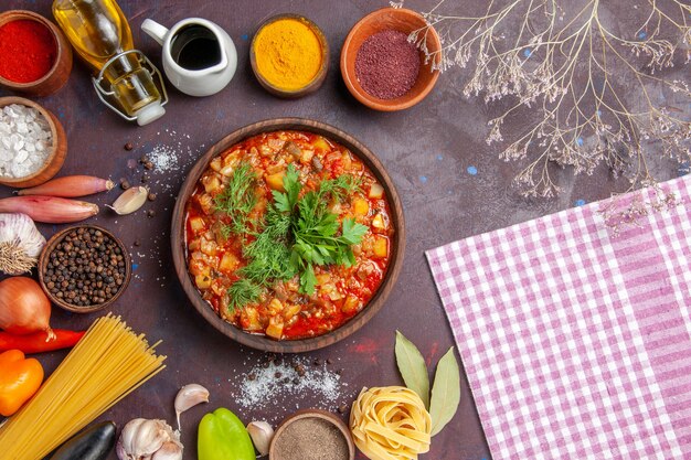 Vue de dessus de savoureux légumes cuits tranchés avec de la sauce et différents assaisonnements sur fond sombre soupe alimentaire soupe dîner