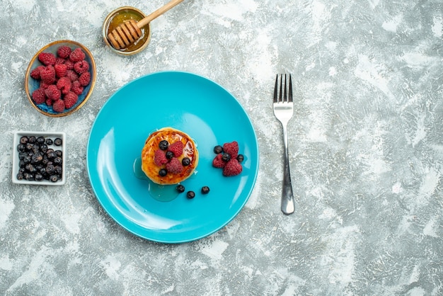 Vue de dessus de savoureux muffins aux baies et au miel sur une surface légère