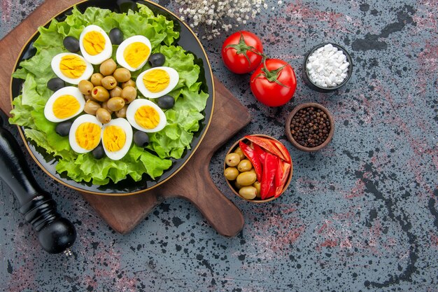 Vue de dessus de savoureux œufs durs avec des olives salade verte et des tomates sur fond clair