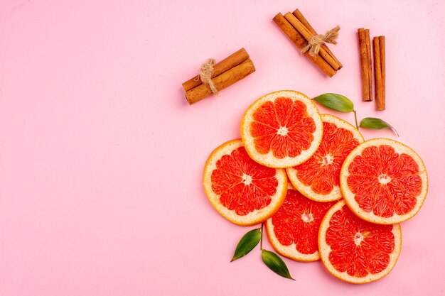 Vue de dessus de savoureux pamplemousses tranches de fruits juteux à la cannelle sur la surface rose