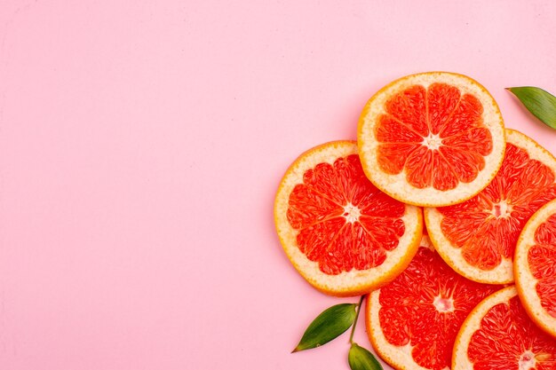 Vue de dessus de savoureux pamplemousses tranches de fruits juteux sur la surface rose