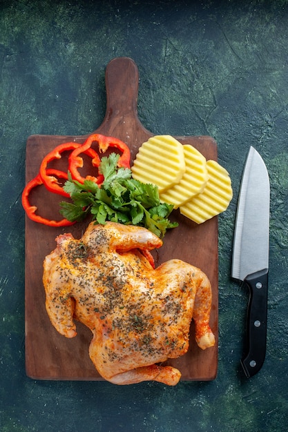 Vue de dessus savoureux poulet cuit épicé avec des pommes de terre et du poivre tranché sur fond sombre plat de couleur de viande dîner repas barbecue