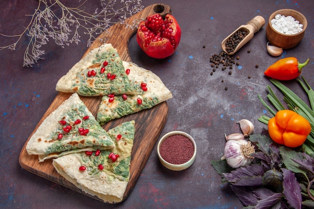 Vue de dessus savoureux qutabs cuits morceaux de pâte avec des verts sur fond noir