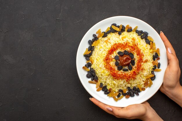 Vue de dessus savoureux repas oriental célèbre se compose de riz cuit et de différents raisins secs sur l'obscurité