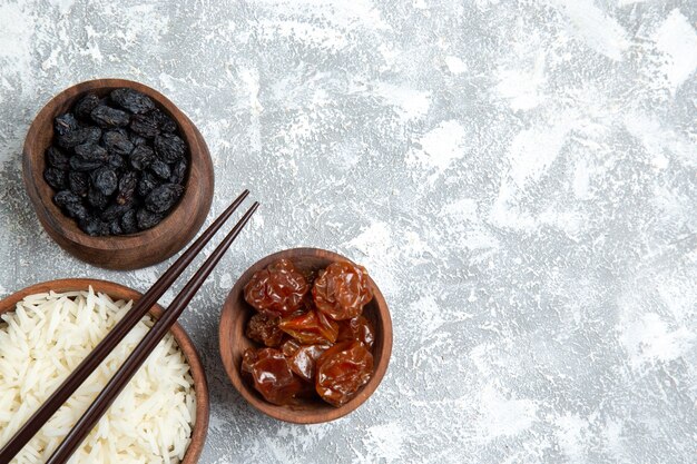 Vue de dessus savoureux riz cuit à l'intérieur de la plaque brune avec des raisins secs sur un bureau blanc clair