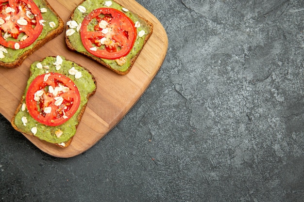 Vue de dessus de savoureux sandwichs à l'avocat avec des tranches de tomates rouges sur le fond gris burger sandwich pain pain snack