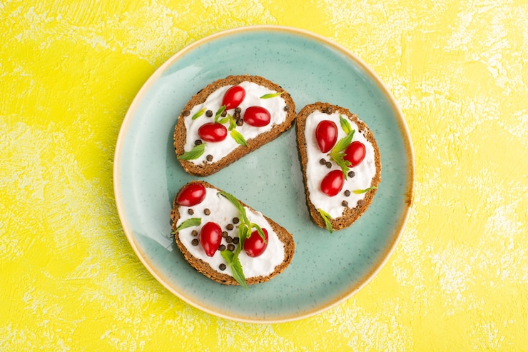 Photo gratuit vue de dessus de savoureux toasts de pain avec de la crème sure et des cornouillers sur la surface jaune