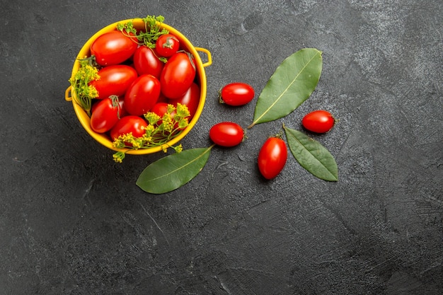 Vue de dessus seau jaune de tomates cerises et de fleurs d'aneth feuilles de laurier et tomates cerises sur le sol sombre avec copie espace