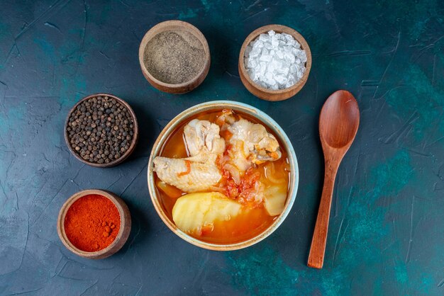 Vue de dessus soupe au poulet avec pommes de terre avec assaisonnements de sel poivre sur le fond bleu foncé soupe viande nourriture dîner repas