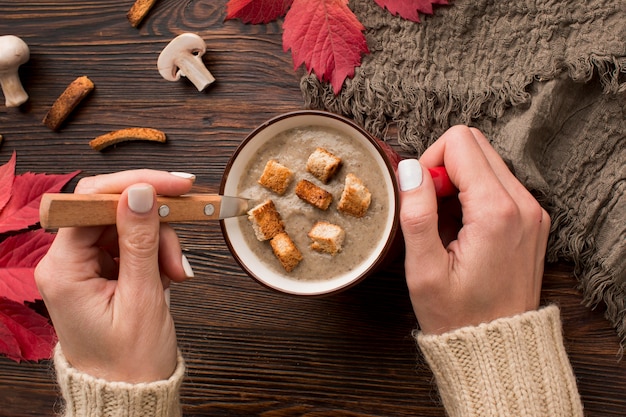 Vue De Dessus De La Soupe Aux Champignons D'hiver Dans La Tasse Avec Les Mains Tenant La Cuillère