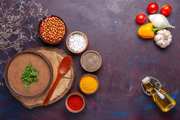 Vue de dessus soupe aux haricots bruns délicieuse soupe cuite avec différents assaisonnements sur la surface sombre dîner soupe repas nourriture aux haricots