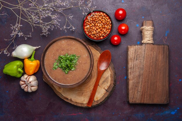 Vue de dessus soupe aux haricots bruns délicieuse soupe cuite avec des légumes sur un bureau sombre soupe aux légumes repas huile alimentaire