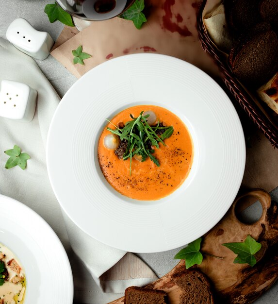 Vue de dessus de la soupe aux légumes garnie d'échalotes et de roquette