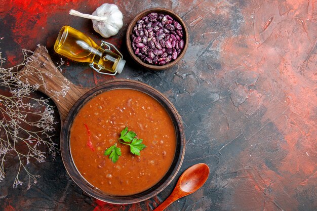 Vue de dessus de la soupe aux tomates sur une planche à découper brune sur une table de couleurs mélangées