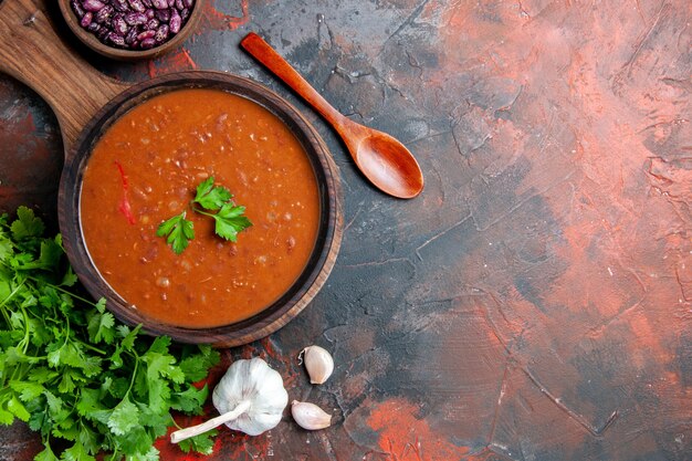 Vue de dessus de la soupe aux tomates sur une planche à découper brune sur une table de couleurs mélangées